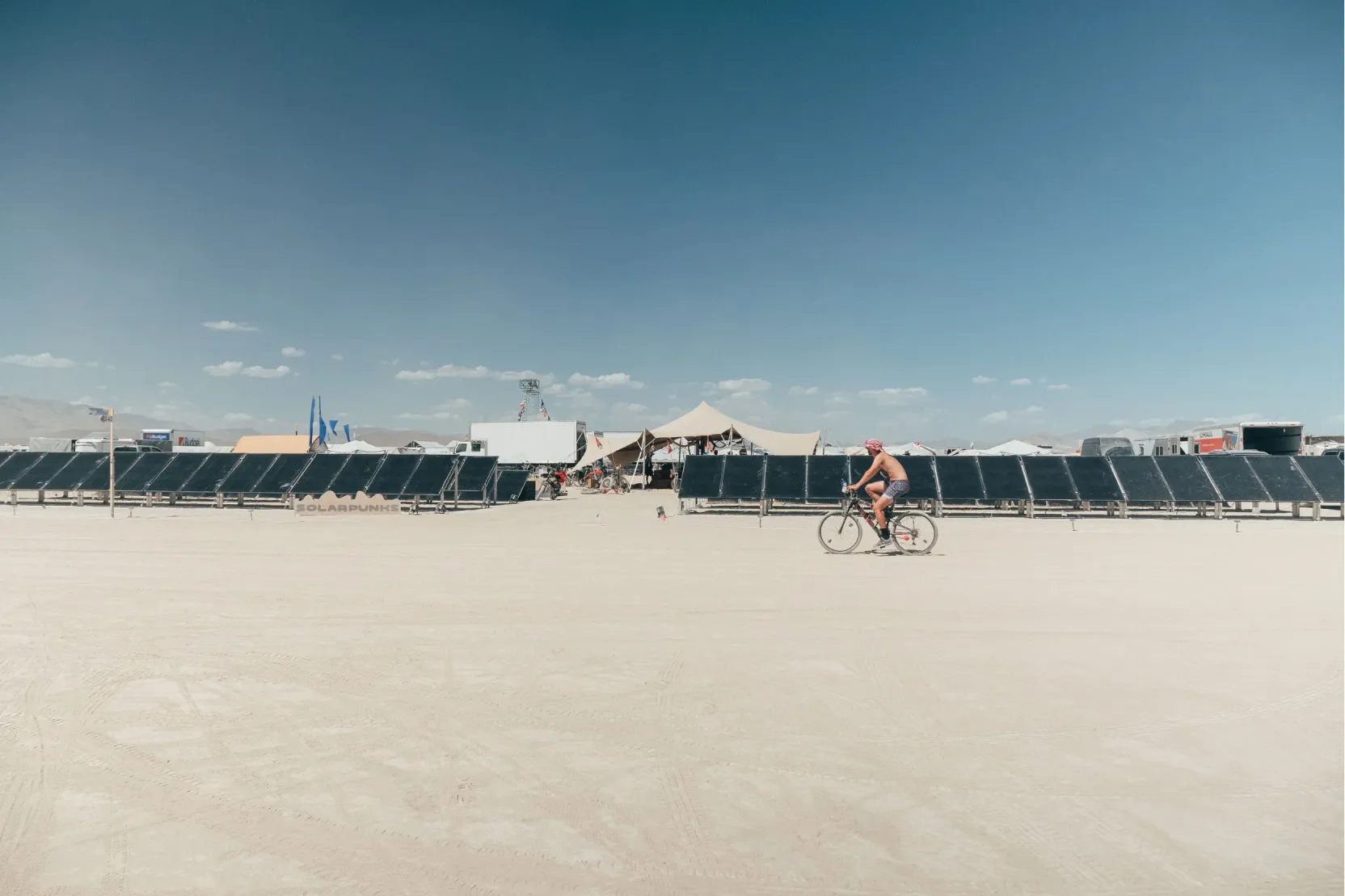 A cyclist riding past a solar array on the playa